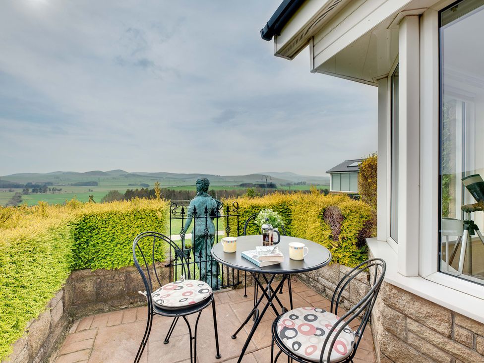 An outdoor seating area with a table and chairs overlooking a landscape at The Granary in Alnwick