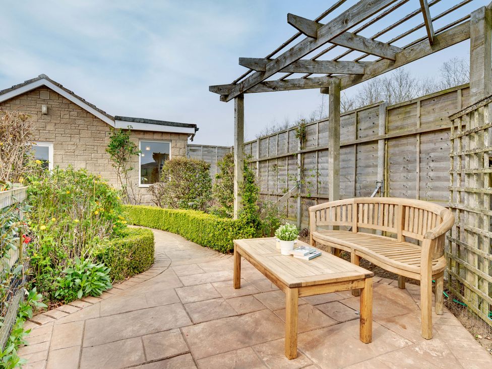 A garden with a stone pathway and wooden bench at The Granary in Alnwick