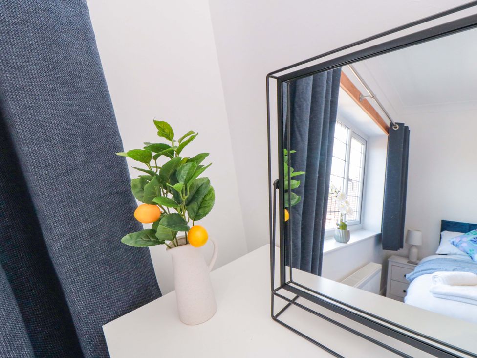 A bedroom with a mirror and a vase of flowers at 60 Muston Road in Filey