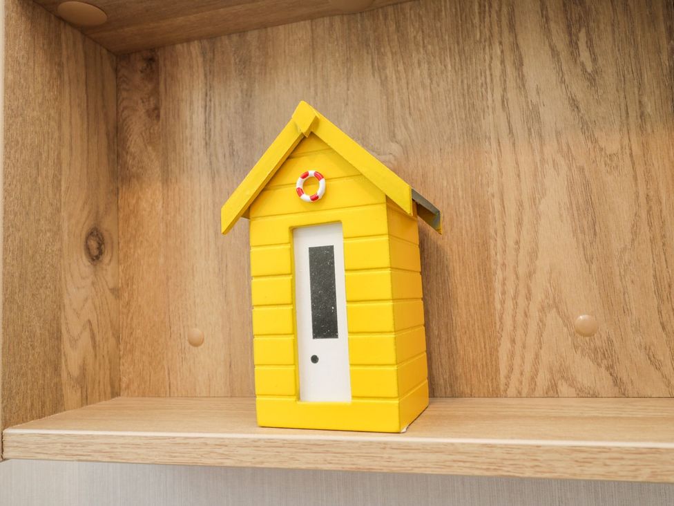 A yellow decorative house on a wooden shelf at Kelly's Retreat in Scarborough