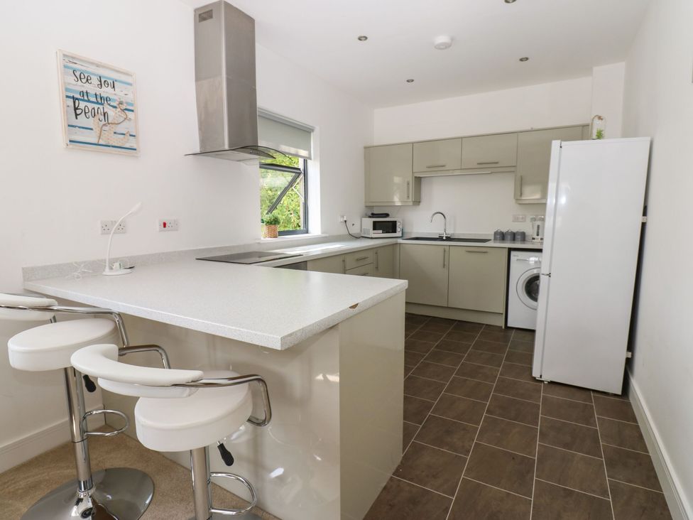 A kitchen with bar stools and appliances at Seaview in Whitehaven