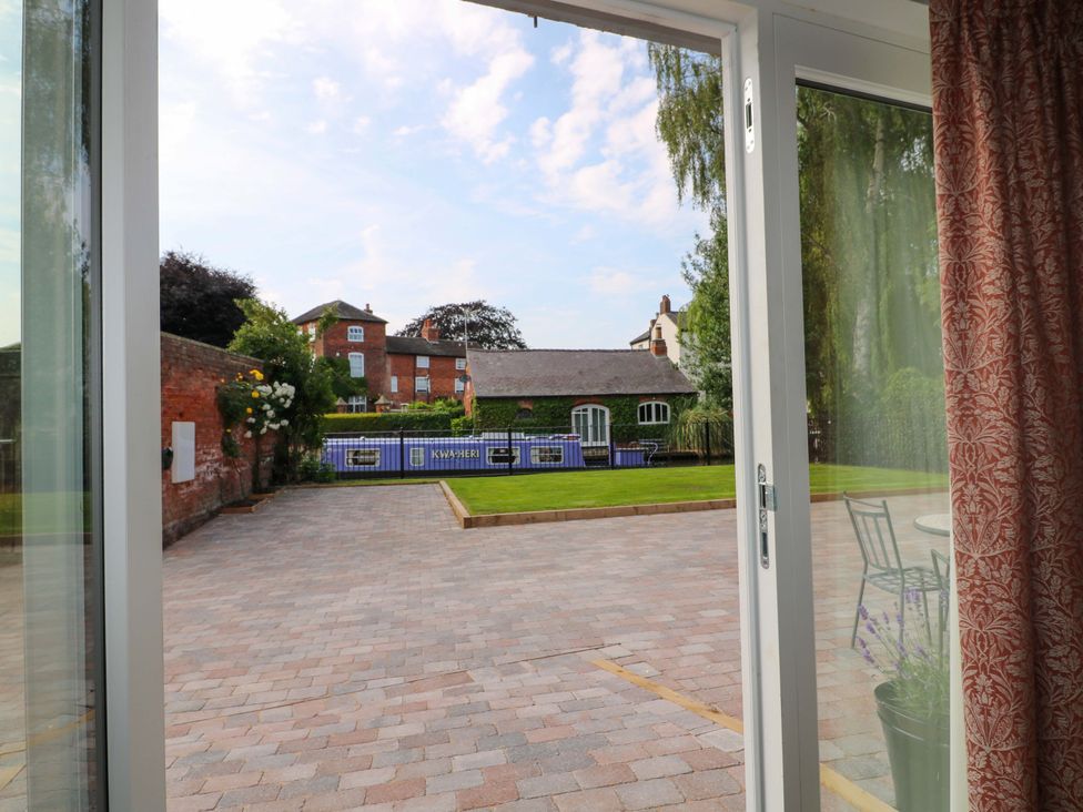 A view from a door showing a garden and buildings at The Canalside Cottage in Derby