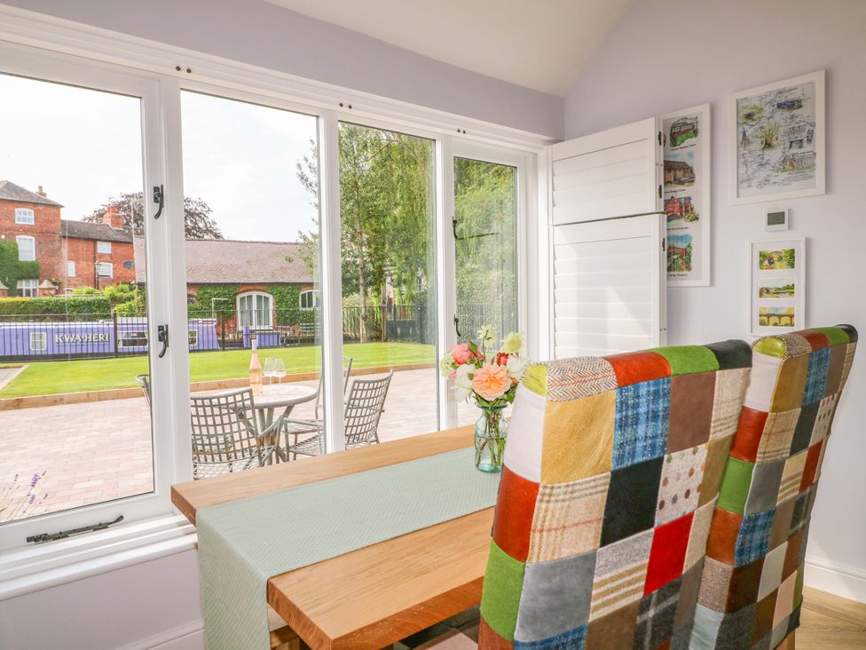 A dining room with a table and chairs overlooking the patio at The Canalside Cottage in Derby
