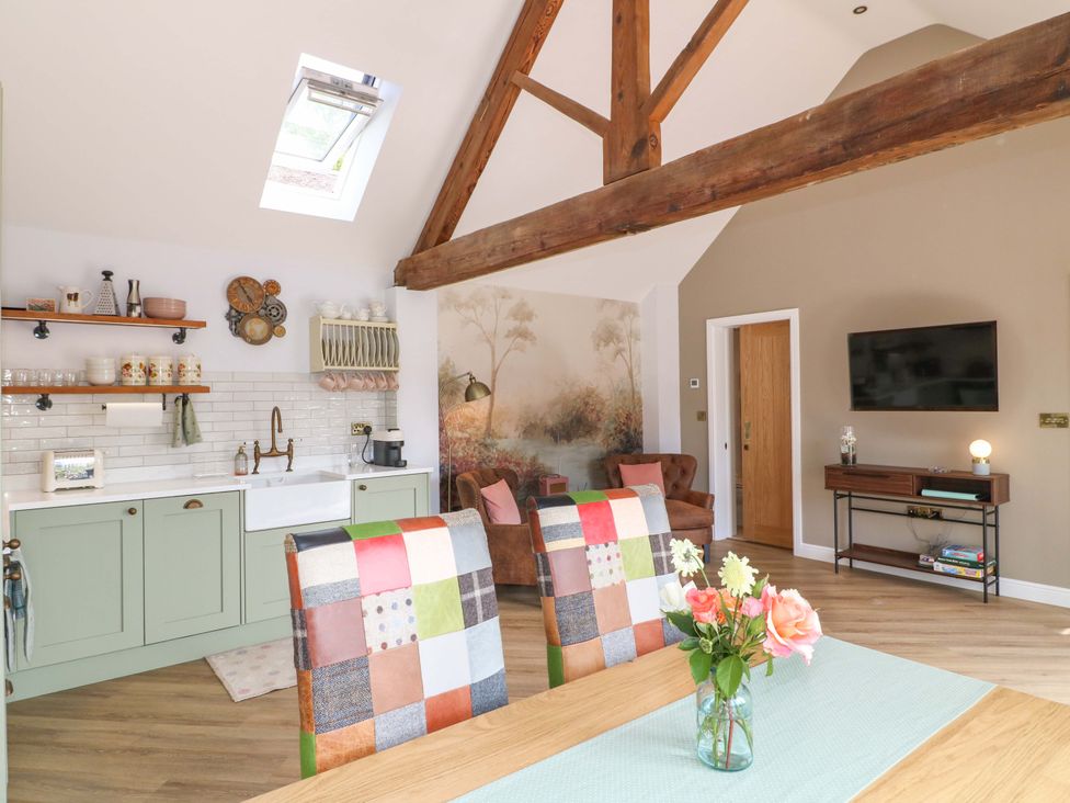 A kitchen and living area with dining table and television at The Canalside Cottage in Derby