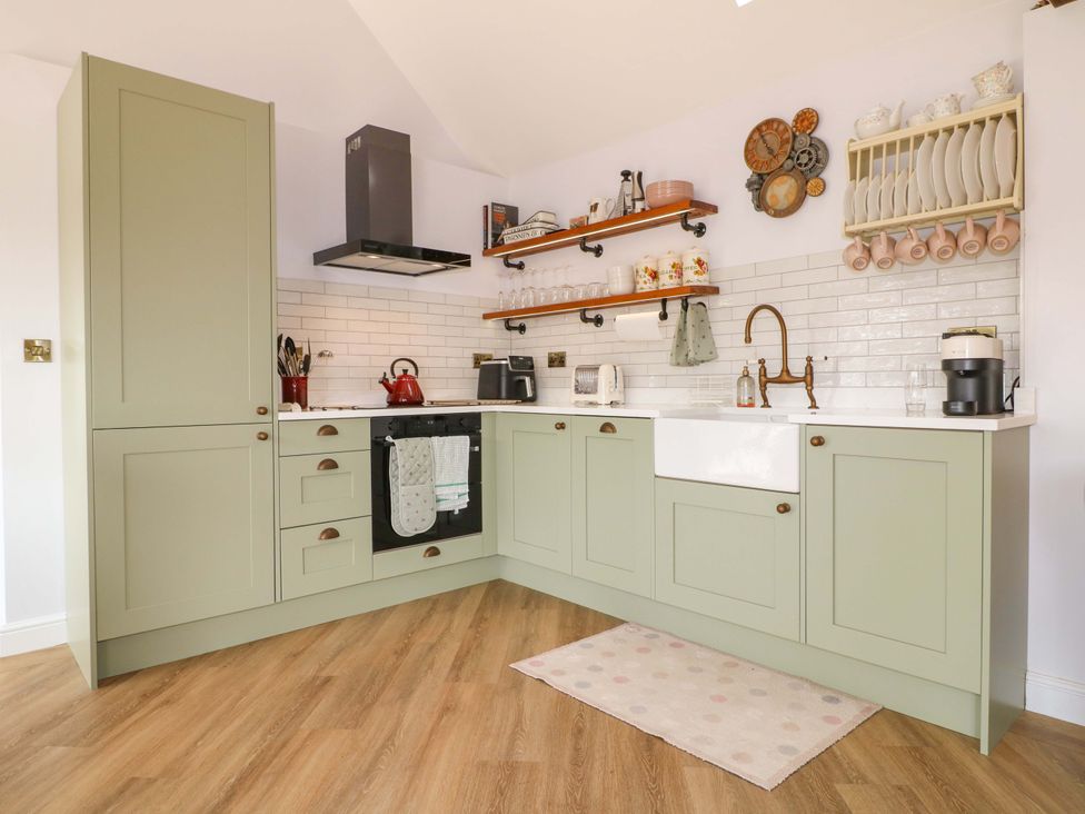A kitchen with cabinets, sink, stove, and shelves at The Canalside Cottage in Derby