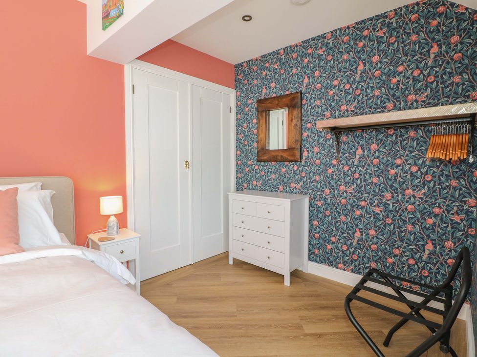 A bedroom with a bed, nightstand, lamp, dresser, and shelves at The Canalside Cottage in Derby