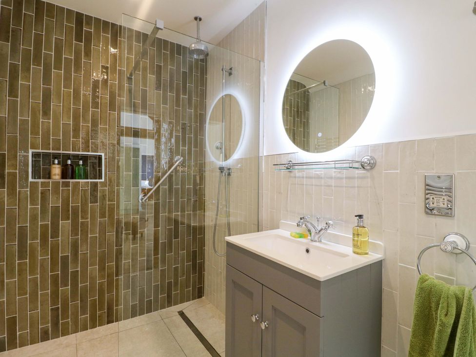 A bathroom with a shower, sink, and mirror at The Canalside Cottage in Derby