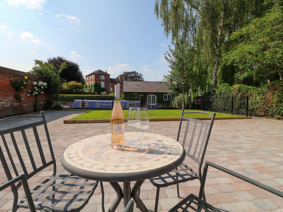 A table with a bottle and glasses in a garden at The Canalside Cottage in Derby