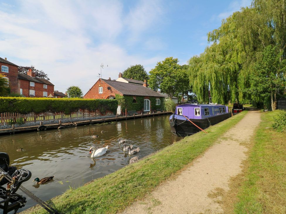 A canal with a house and a boat at The Canalside Cottage Derby