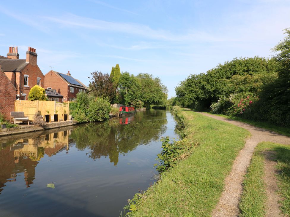 A canal with houses and a boat along the side at The Canalside Cottage in Derby