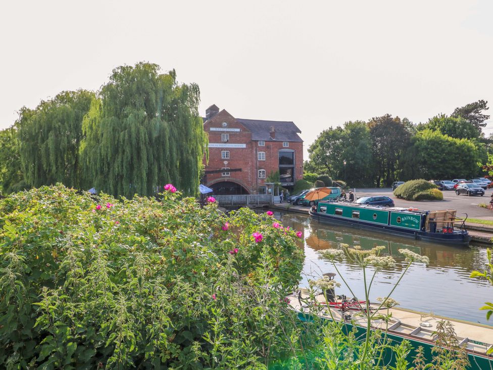 A canal with a boat and a house beside it at The Canalside Cottage Derby