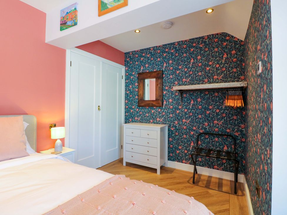 A bedroom with a bed, dresser, and shelf at The Canalside Cottage in Shardlow near Castle Donington