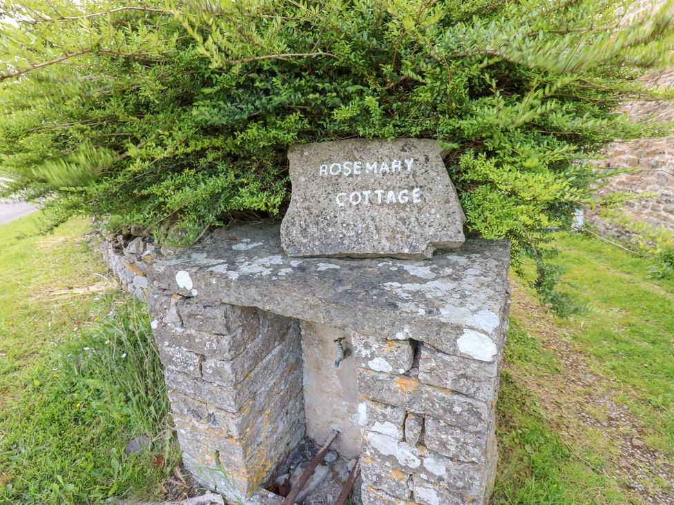 A stone sign for Rosemary Cottage surrounded by grass and bushes at Rosemary Cottage in Leyburn