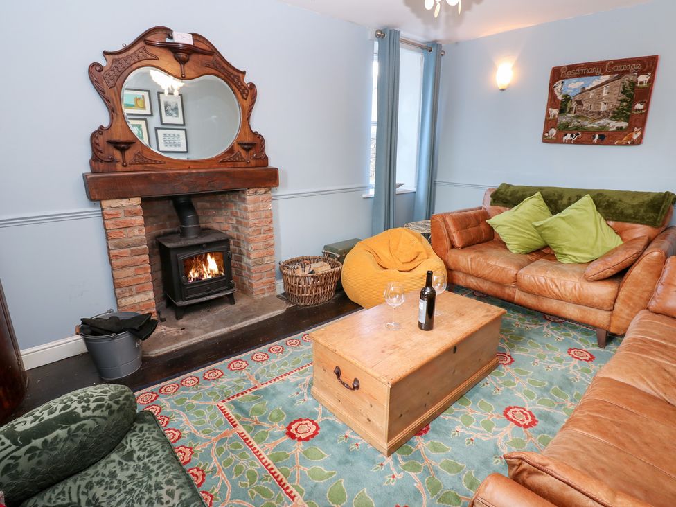 A living room with a fireplace and seating at Rosemary Cottage Leyburn