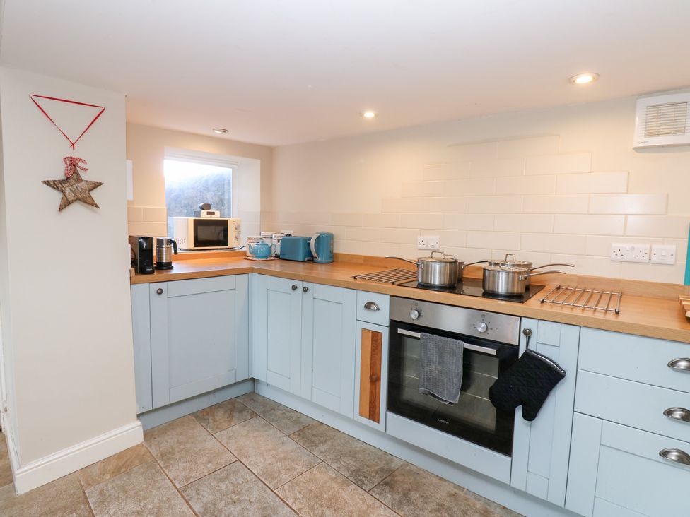 A kitchen with pots on the stove and a microwave at Rosemary Cottage in Leyburn