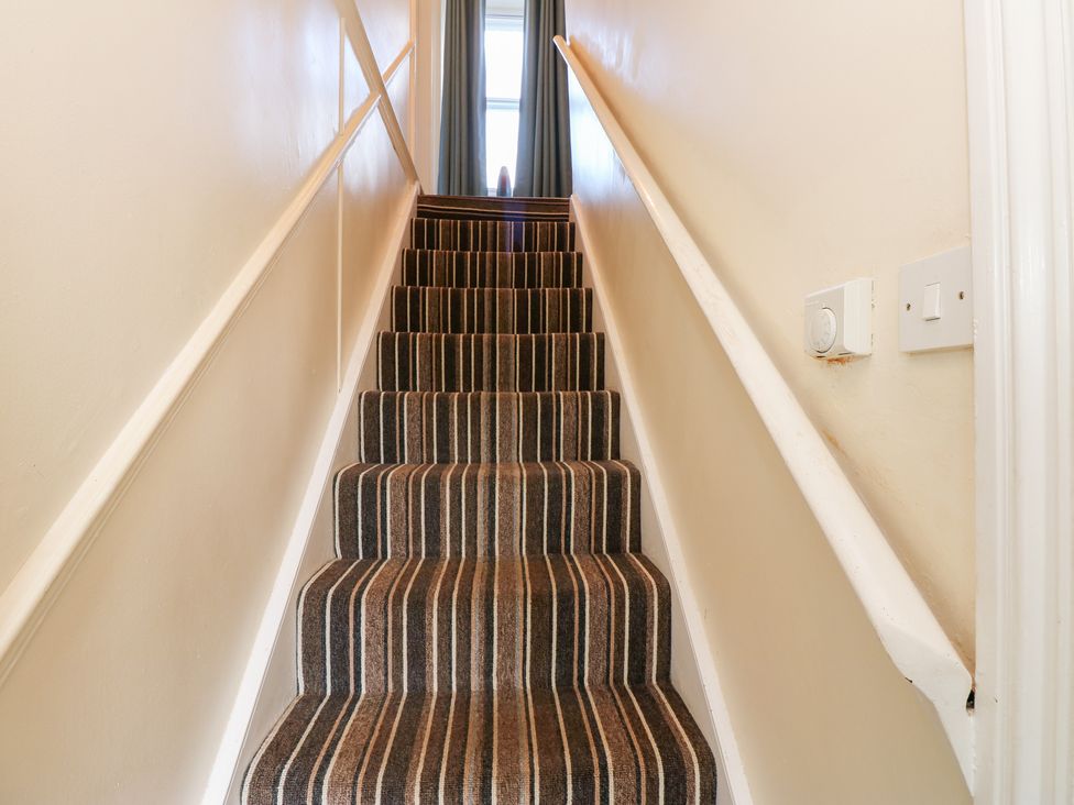 A staircase with striped carpet at Rosemary Cottage in Leyburn