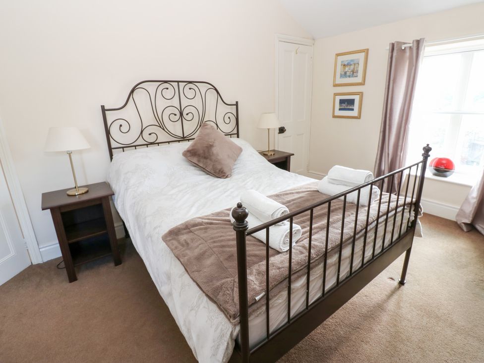 A bedroom with a bed and nightstand at Rosemary Cottage in Leyburn
