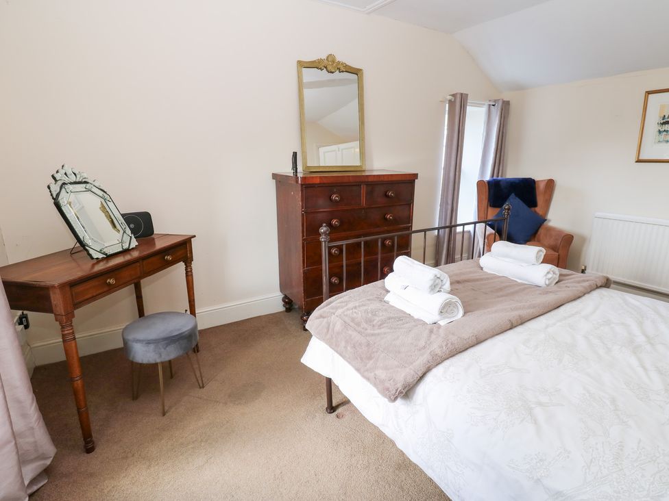 A bedroom with a bed, dressing table, and chest of drawers at Rosemary Cottage Leyburn