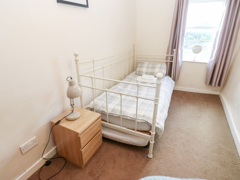 A bedroom with a single bed and a bedside lamp at Rosemary Cottage Leyburn