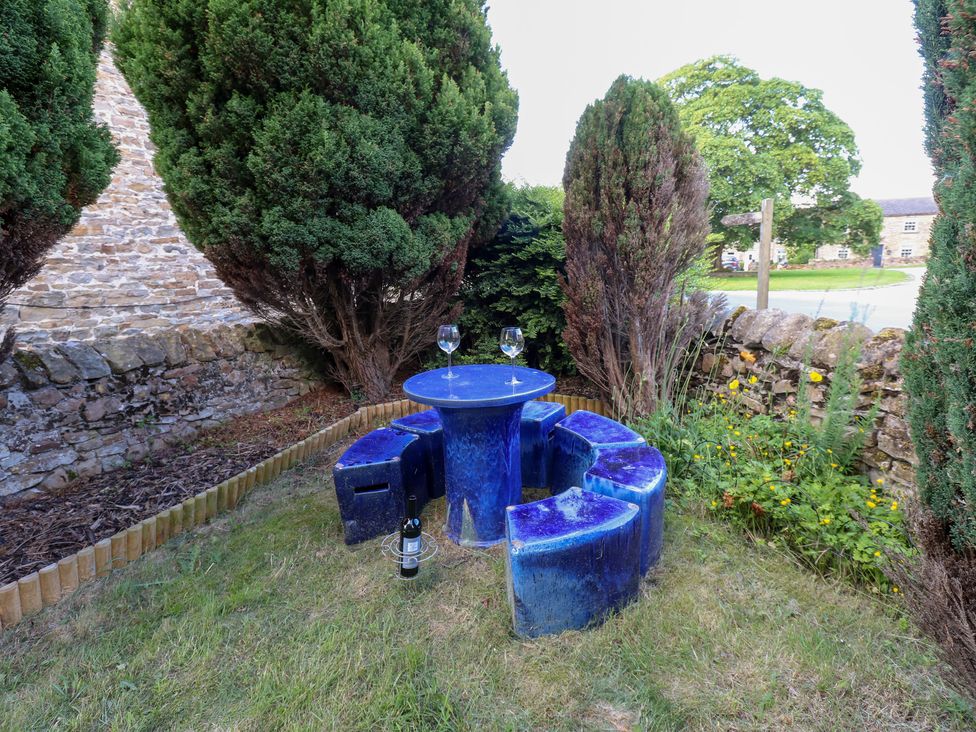 A garden area with a blue table and seating at Rosemary Cottage Leyburn