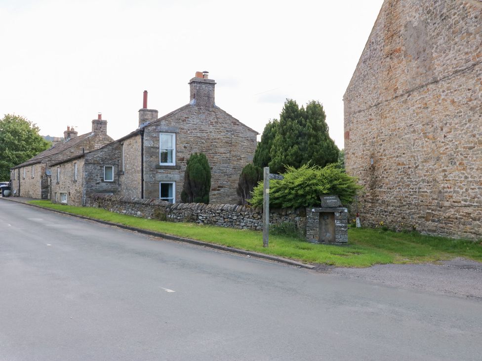 A row of houses with stone walls and a road at Rosemary Cottage in Leyburn