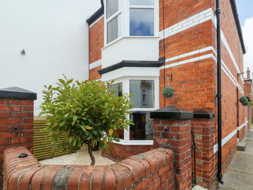 An exterior view of a brick house with a small tree and pathway at Otter Cottage in Weymouth