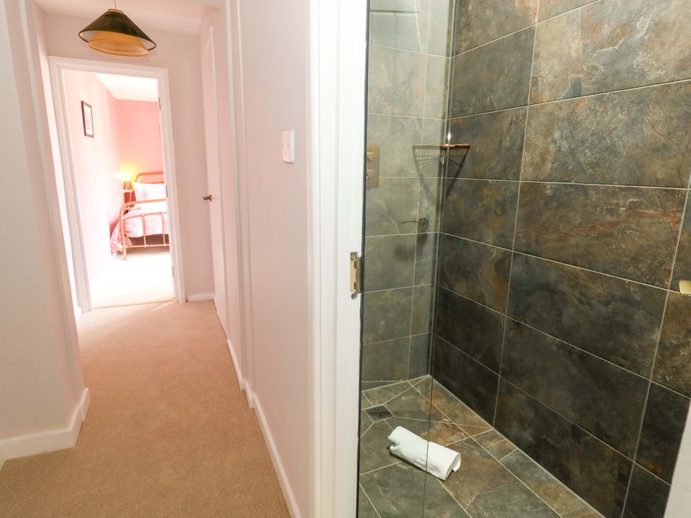 A shower with a towel and a view of a hallway at Otter Cottage in Weymouth