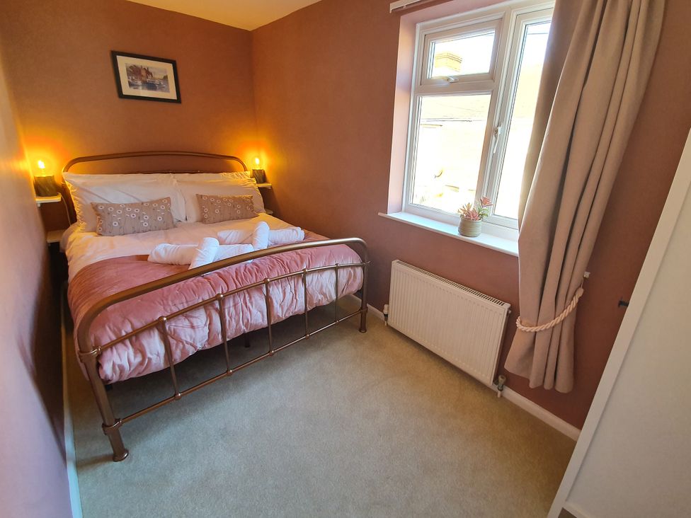 A bedroom with a bed and window at Otter Cottage in Weymouth