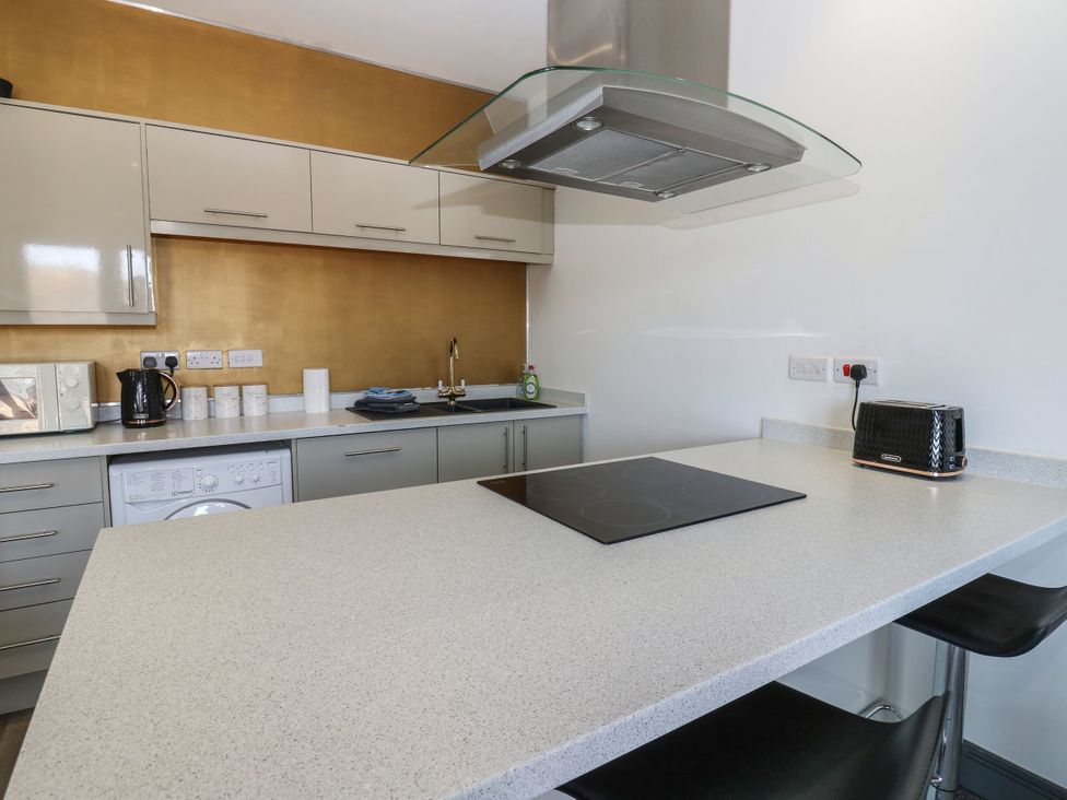 A kitchen with countertop, cabinets, washing machine, and appliances at Quayside Apartments Whitehaven