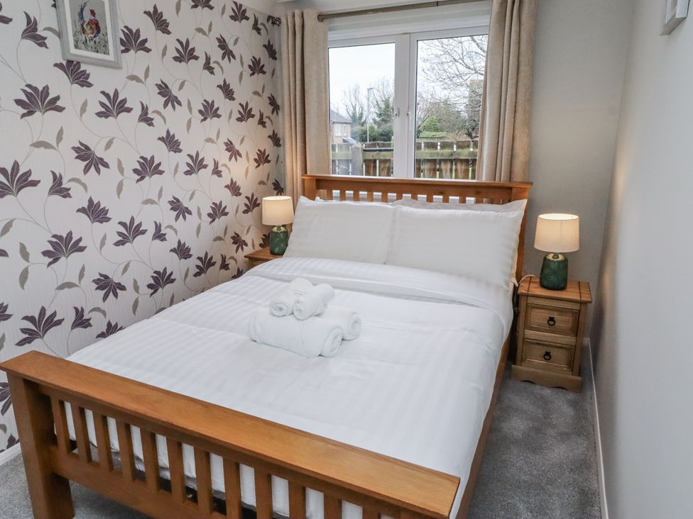 A bedroom with a double bed and lamps at 26 Blakelaw Court in Alnwick