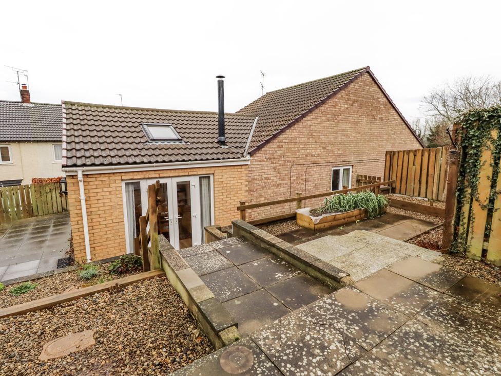 An outdoor area with a brick house and garden bed at 26 Blakelaw Court in Alnwick