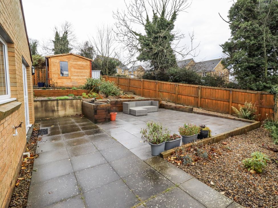 A garden with paving stones and a wooden shed at 26 Blakelaw Court in Alnwick
