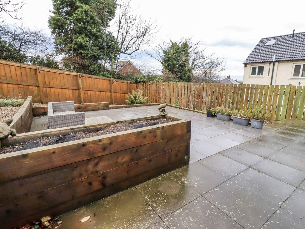 A garden with patio, wooden planter and outdoor furniture at 26 Blakelaw Court in Alnwick