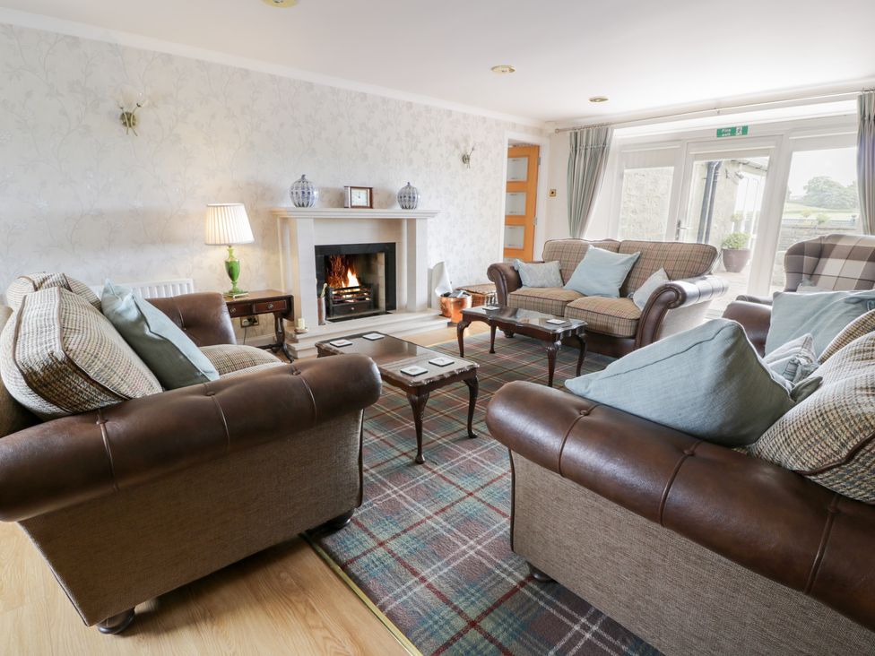 A living room with a fireplace and seating area at Marshill Farm house in Lanark