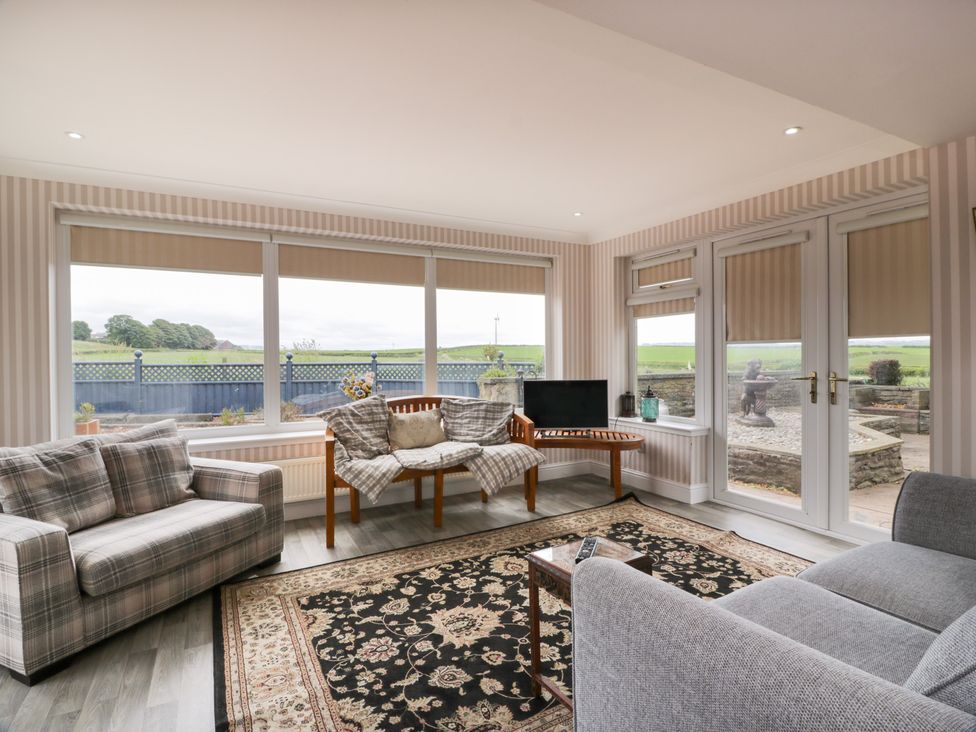 A conservatory with seating and a television at Marshill Farm house Lanark