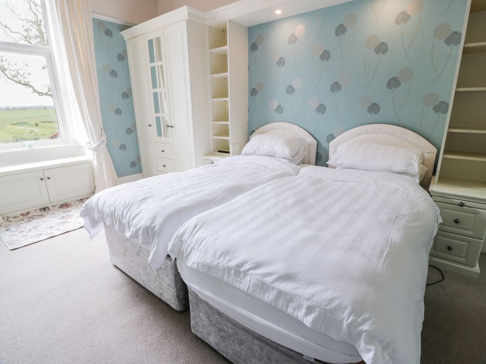 A bedroom with two beds and a wardrobe at Marshill Farm house in Lanark