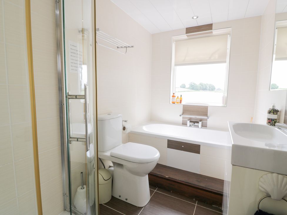 A bathroom with a shower, bathtub and sink at Marshill Farm house in Lanark