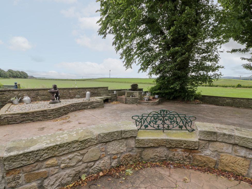 An outdoor area with a stone wall and a statue at Marshill Farm house in Lanark