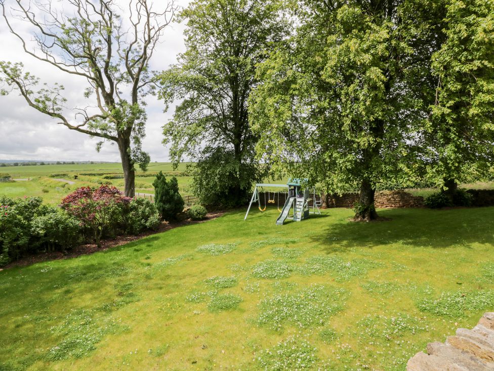A garden with a playground and trees at Marshill Farm house in Lanark