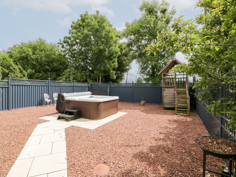 A garden with a hot tub and a playhouse at Marshill Farm house in Lanark