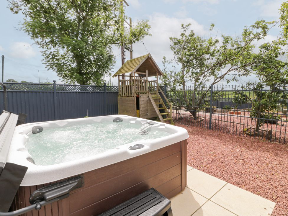 A hot tub and a playhouse in the garden at Marshill Farm house in Lanark