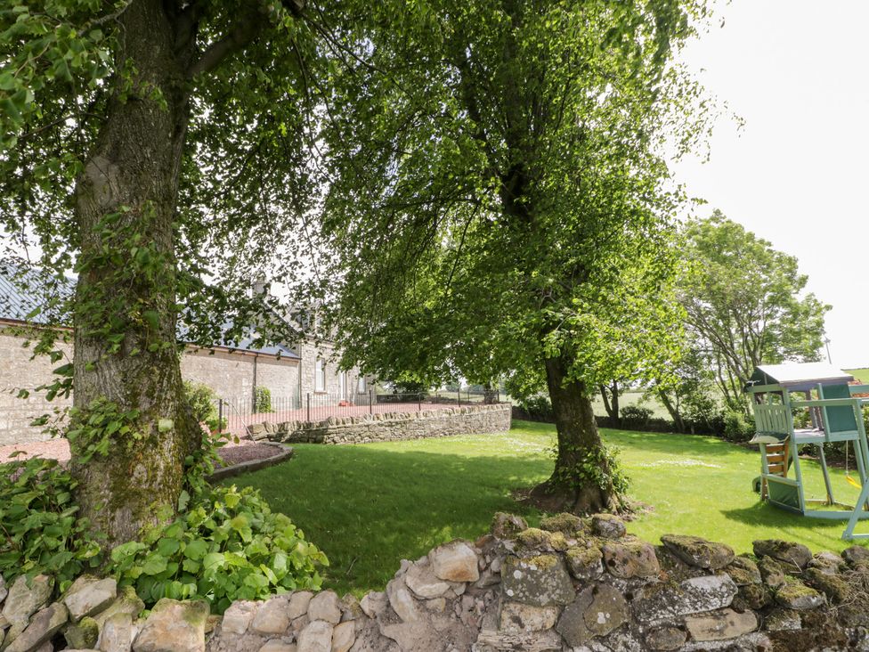 A garden with trees and a playground structure at Marshill Farm house in Lanark