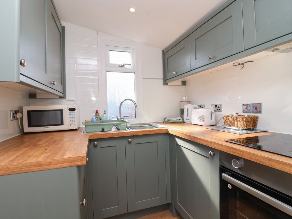 A kitchen with a microwave sink and kettle at Stella Maris in Torpoint