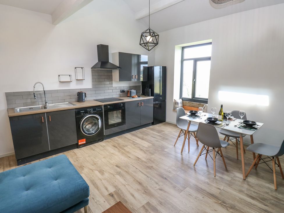A kitchen with appliances and dining table at Myrtle Loft in Keighley