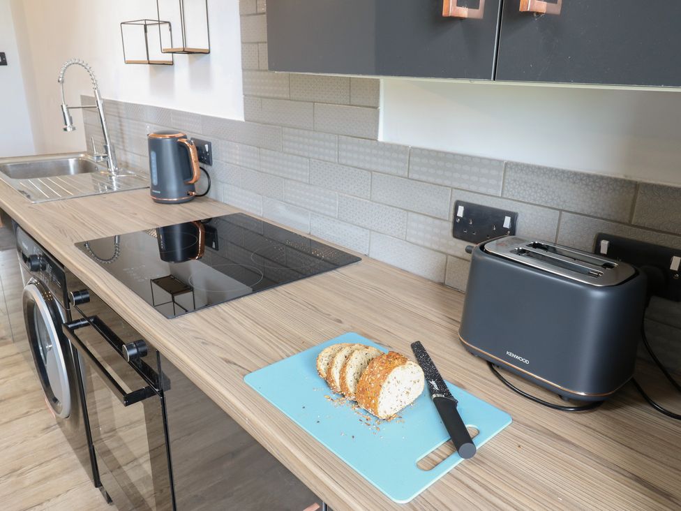 A kitchen with a sink, kettle, induction cooktop, and toaster at Myrtle Loft in Keighley