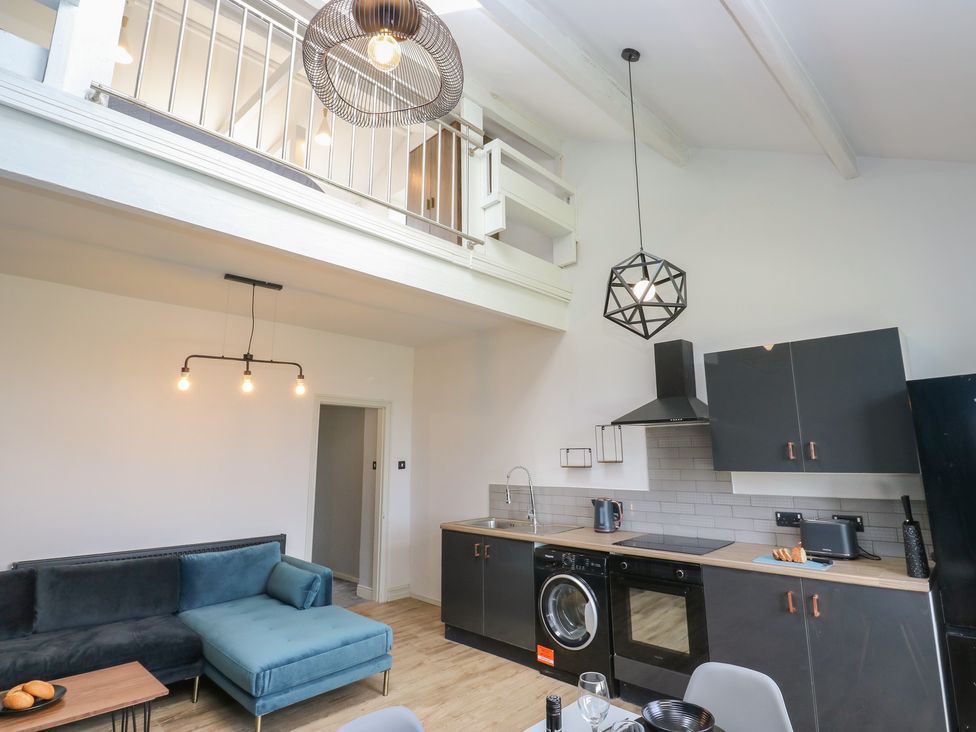 A living room with a sofa and kitchen area at Myrtle Loft Keighley