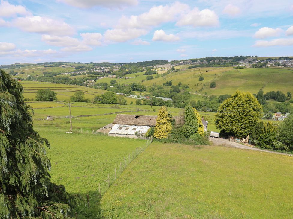 A view of a barn and farmland with hills in the distance at Myrtle Loft in Keighley