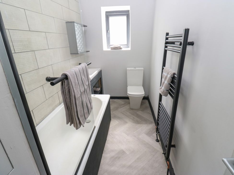 A bathroom with a bathtub, toilet, and towel rack at Myrtle Loft in Keighley
