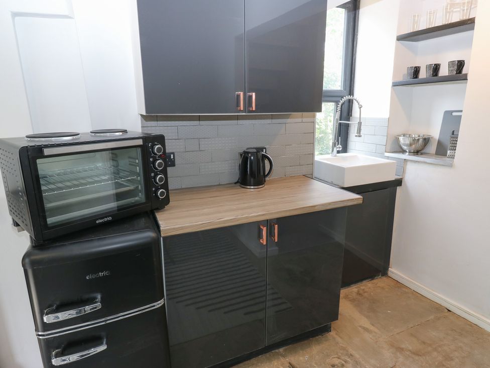 A kitchen with a sink and kitchen appliances at Myrtle Nook in Keighley