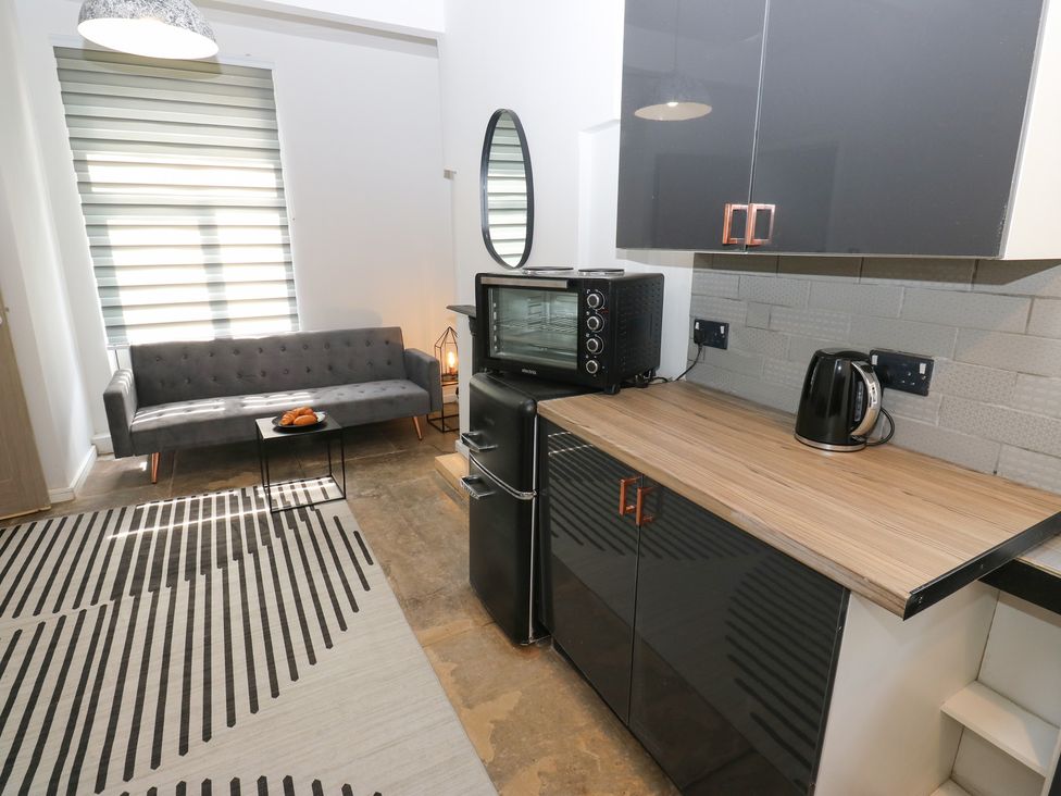 A kitchen/living room with a sofa and kitchen appliances at Myrtle Nook in Keighley